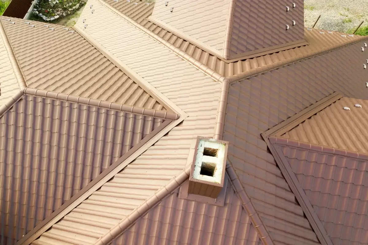 House roof surface covered with brown metal tile sheets.